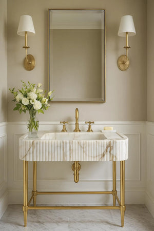 Bathroom vanity with marble sink, gold fixtures, and wall sconces.